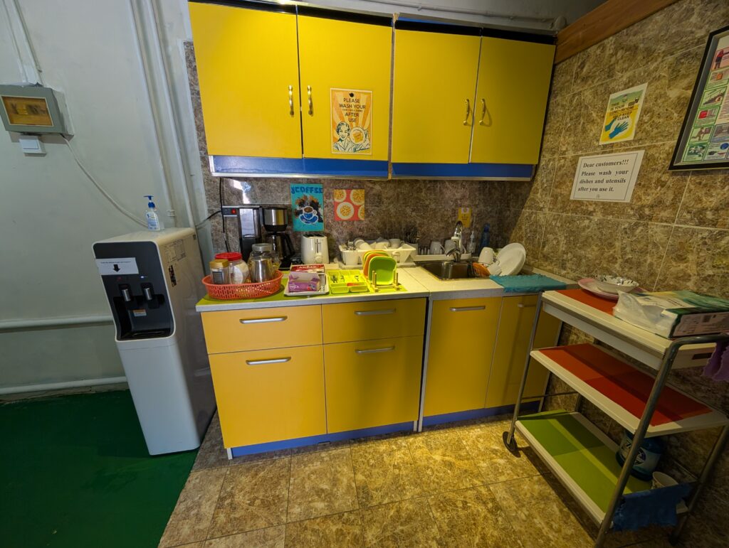 コーヒーメーカーと黄色いキャビネットが並ぶセルフサービスのキッチンスペース