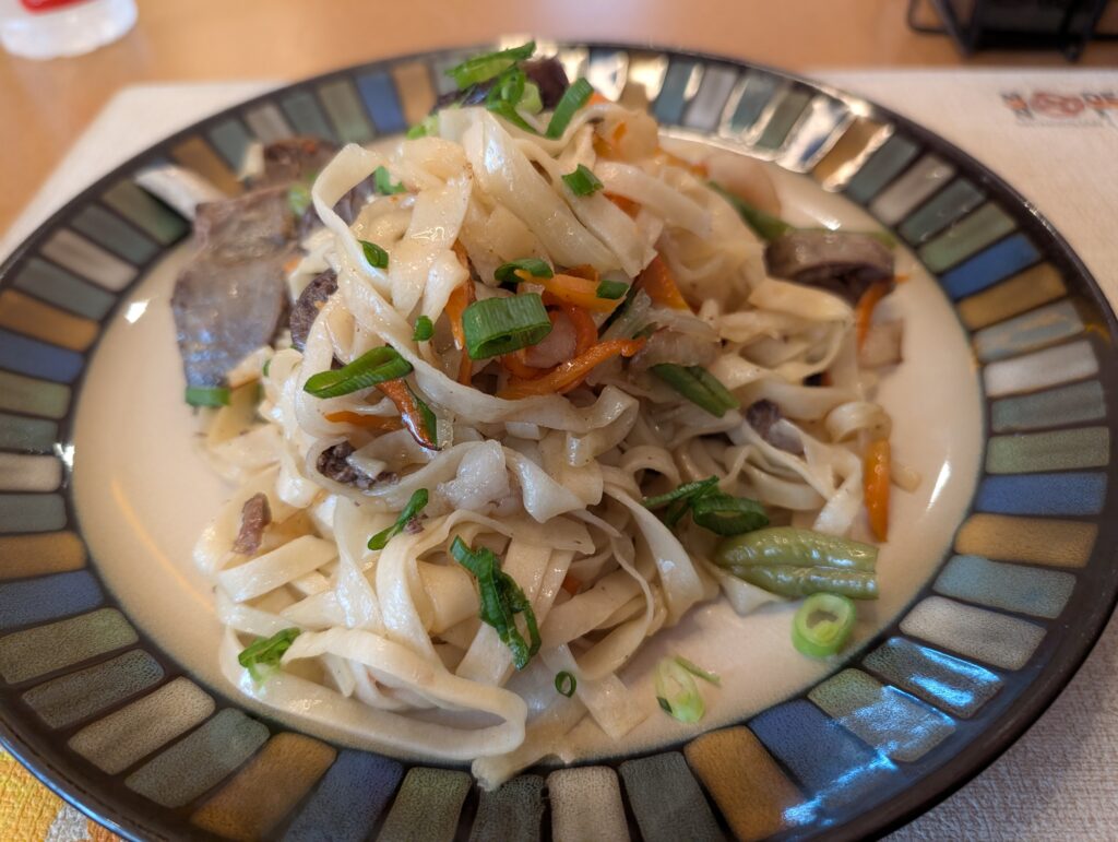 運ばれてきたツォイワン。平打ち麺の上に骨付き肋肉とビーフソーセージ