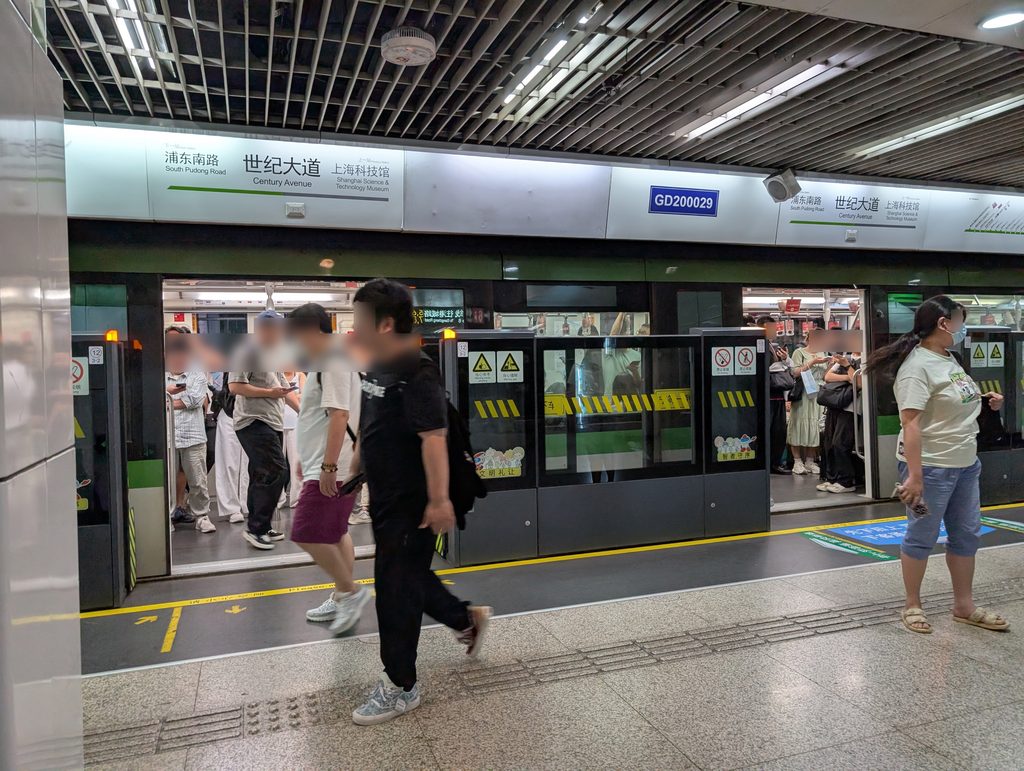 上海地下鉄・世紀大道駅のホーム。ドアが開いて乗り降りする人たち