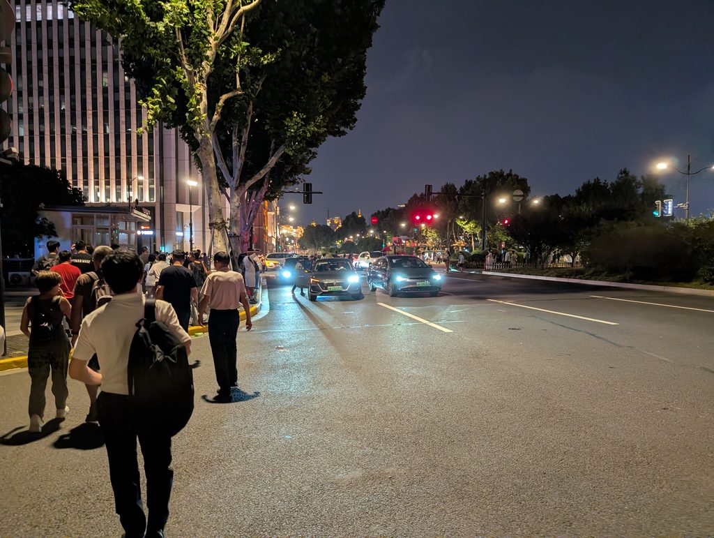 夜の上海・車が行き交う大通りと歩道を歩く人