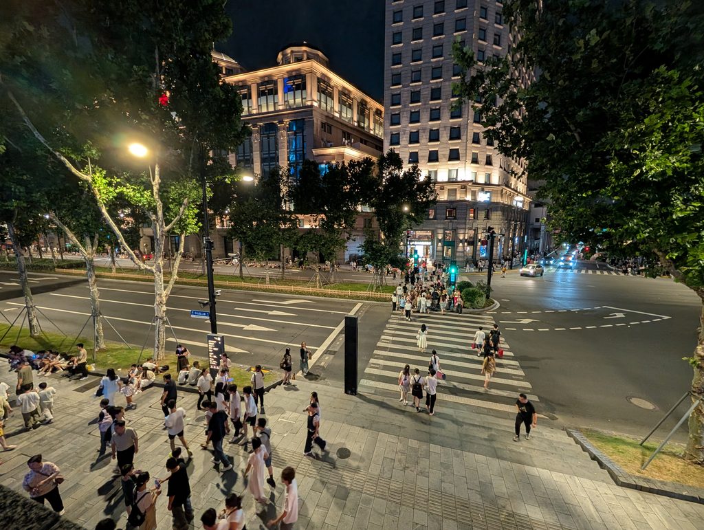 夜の上海・中山東二路の道路標識と横断歩道を渡る人