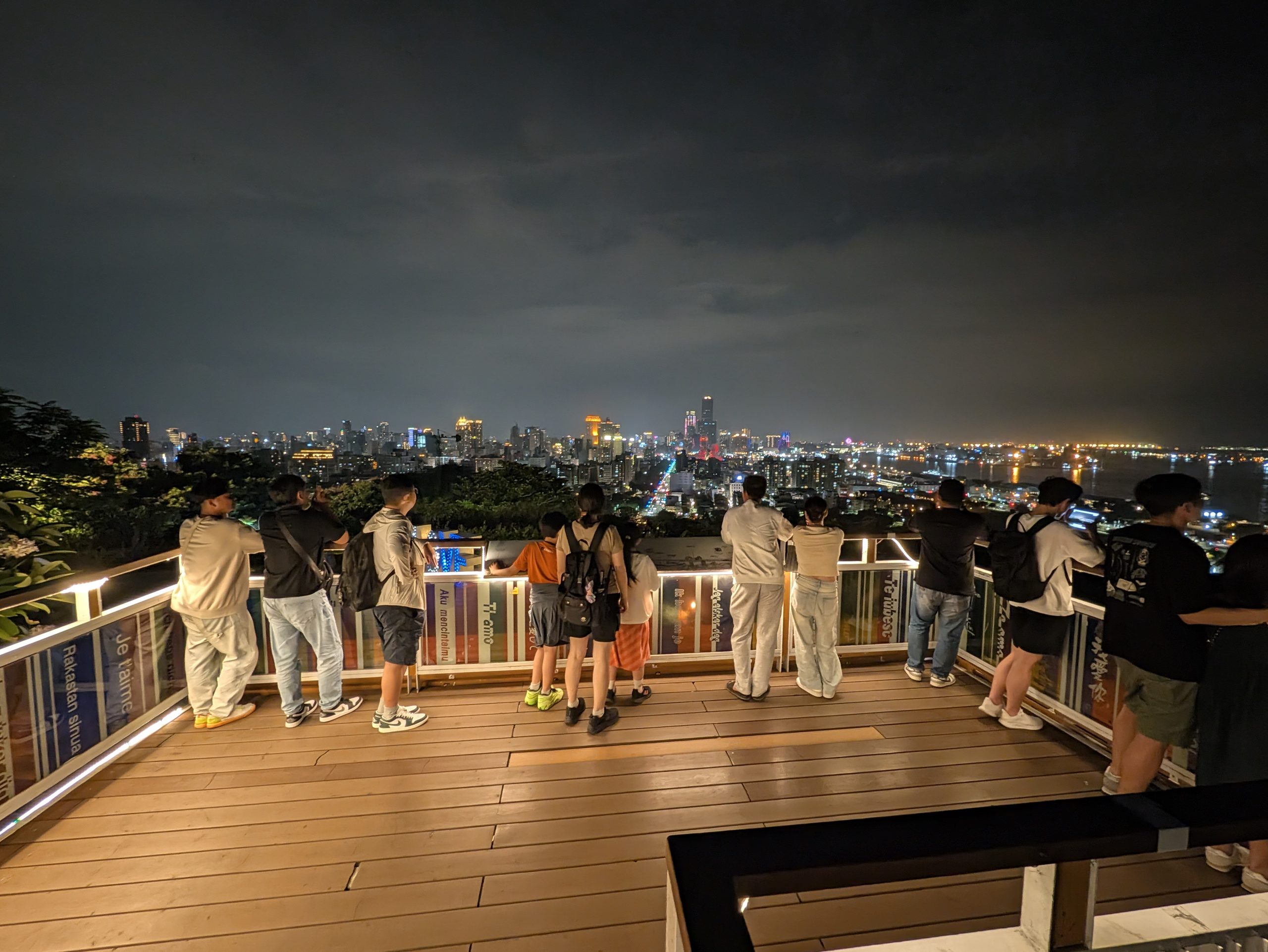 寿山情人観景台の展望デッキから夜景を見る人たち。手すりには各国語の「愛してる」